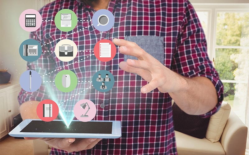 Person holding tablet with holographic interface of colorful icons representing digital tools and apps